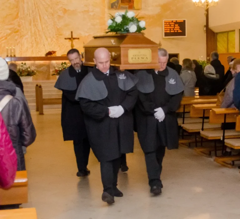 Pracownicy zakładu pogrzebowego wynoszą trumnę z kościoła. Pogrzeb tradycyjny w Gdańśku.