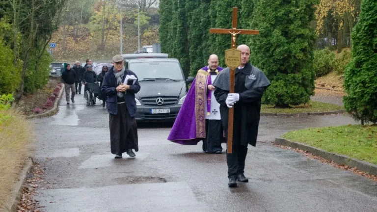 Obsługa pogrzebu tradycyjnego w Gdańsku. Żałobnik zakładu pogrzebowego przystań niesie krzyż na pogrzebie.
